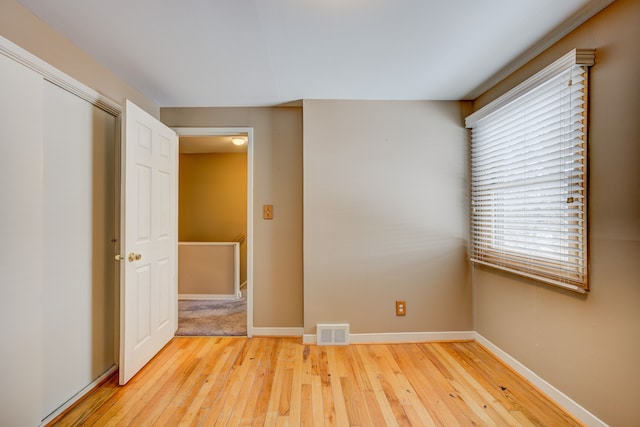 unfurnished bedroom featuring light wood finished floors, a closet, visible vents, and baseboards