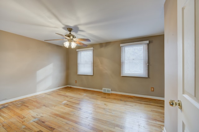 empty room featuring a wealth of natural light, baseboards, visible vents, and light wood finished floors