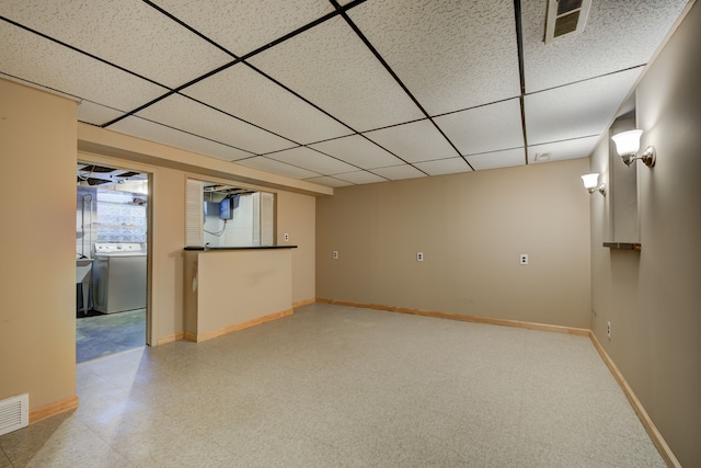 basement with washer / clothes dryer, a drop ceiling, visible vents, and baseboards