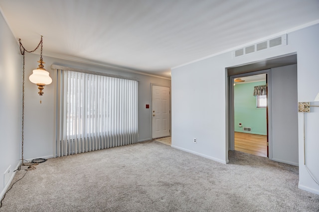 unfurnished room featuring light carpet, crown molding, visible vents, and baseboards