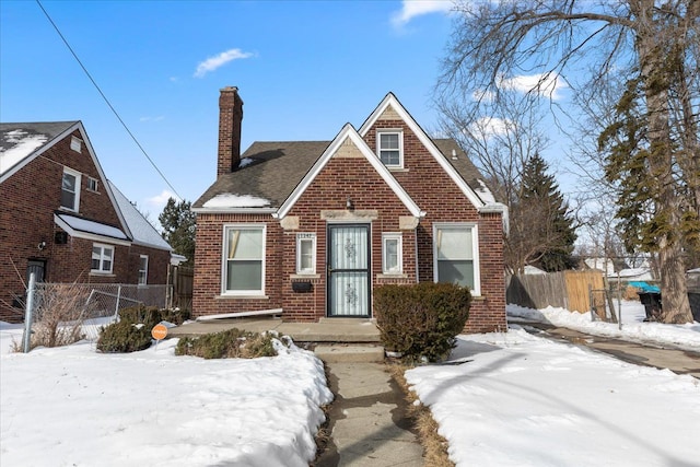 view of front of house with a chimney, fence, and brick siding