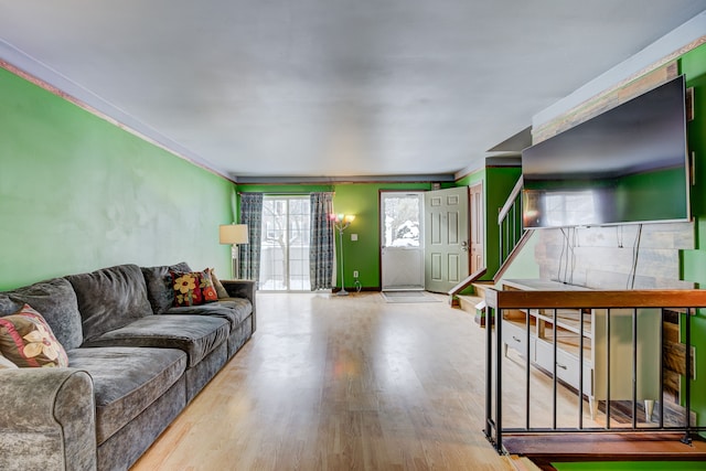 living room with stairs, light wood-style flooring, and crown molding