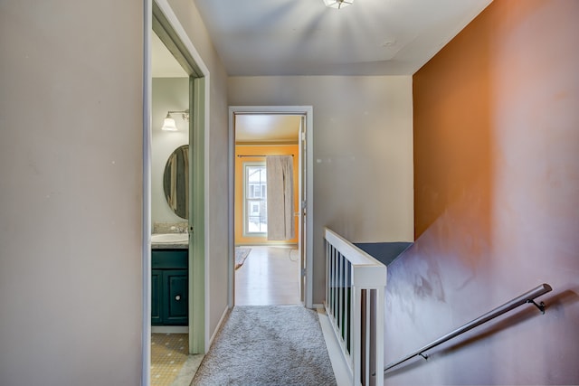 hallway featuring baseboards, light colored carpet, and an upstairs landing