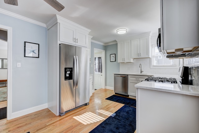 kitchen with stainless steel appliances, backsplash, white cabinetry, and crown molding