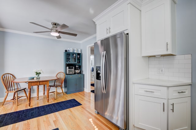 kitchen featuring white cabinets, light countertops, ornamental molding, stainless steel fridge with ice dispenser, and tasteful backsplash