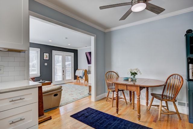 dining room with light wood finished floors, baseboards, a ceiling fan, ornamental molding, and french doors