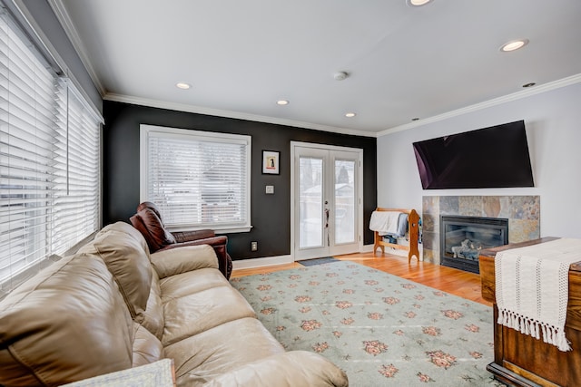 living room featuring light wood-style flooring, recessed lighting, a fireplace, french doors, and ornamental molding