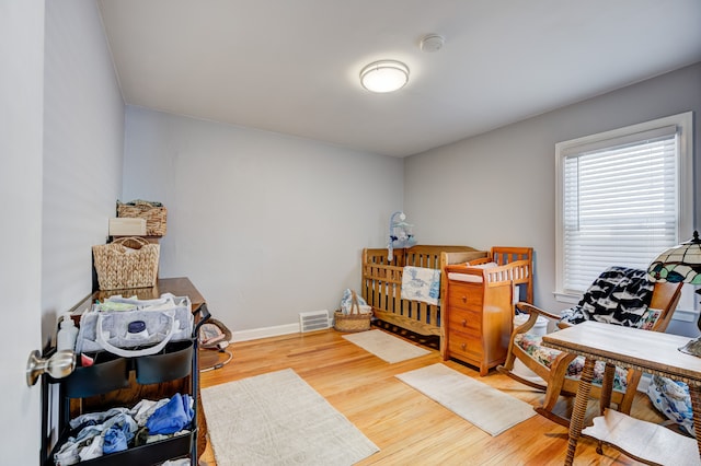 bedroom featuring wood finished floors, visible vents, and baseboards