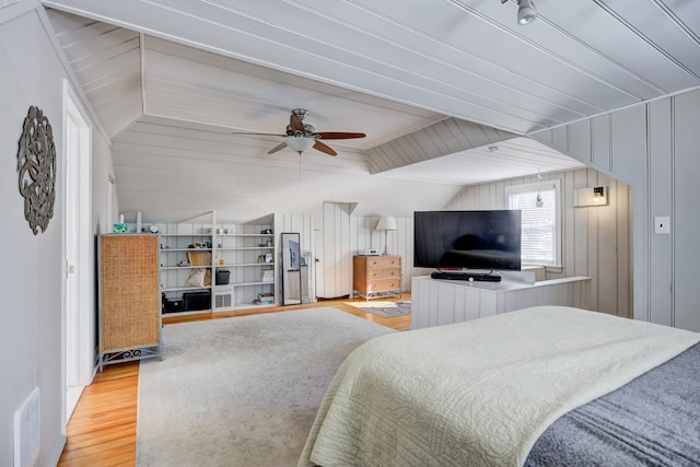 bedroom featuring visible vents, wood walls, light wood-style flooring, and ceiling fan