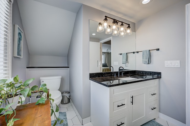 bathroom featuring baseboards, vaulted ceiling, vanity, and toilet