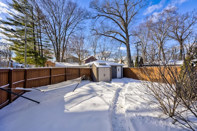 yard covered in snow featuring a shed, fence, and an outbuilding