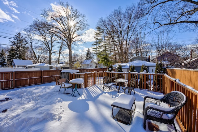 snow covered deck featuring a residential view and fence