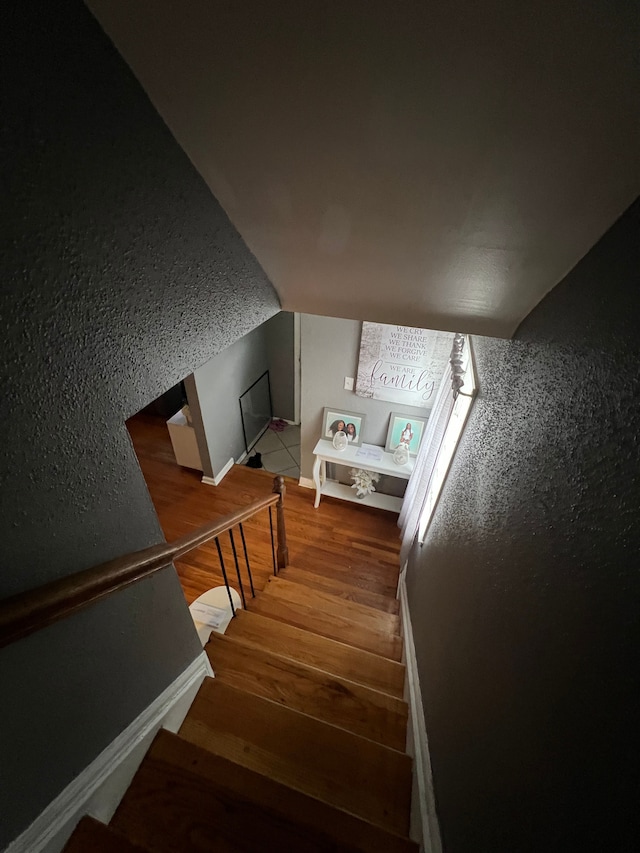 staircase with lofted ceiling and wood finished floors