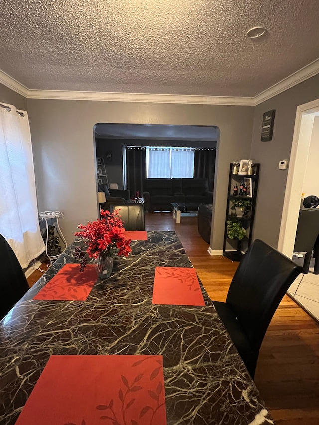 dining room with crown molding, a textured ceiling, and wood finished floors