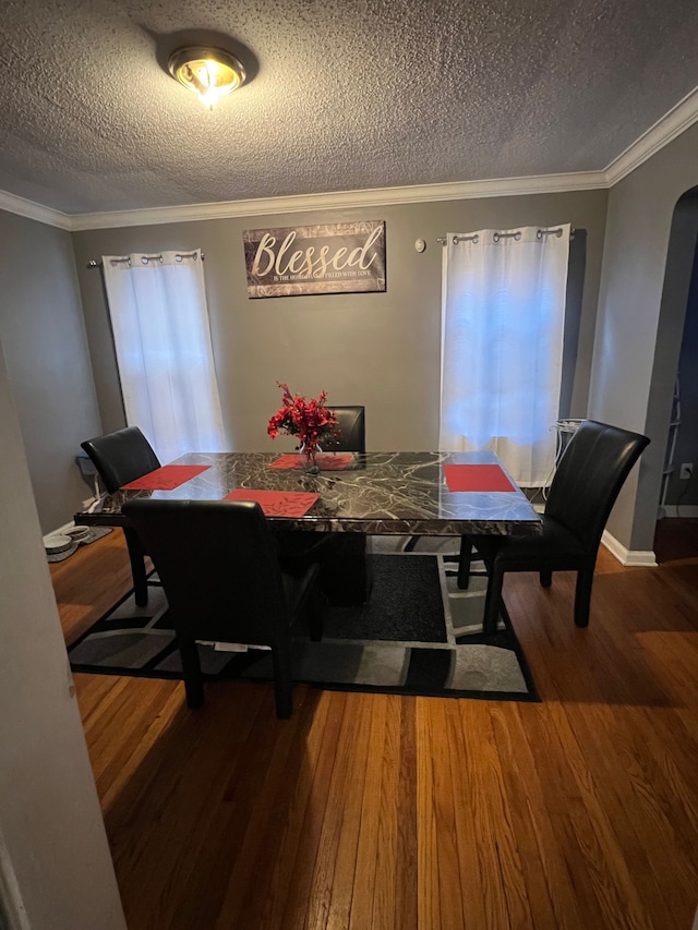 dining space with arched walkways, ornamental molding, a textured ceiling, and dark wood-style floors