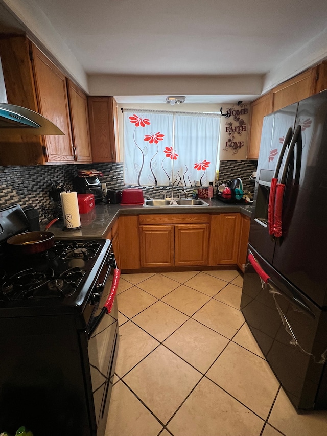 kitchen with dark countertops, black appliances, brown cabinets, and a sink