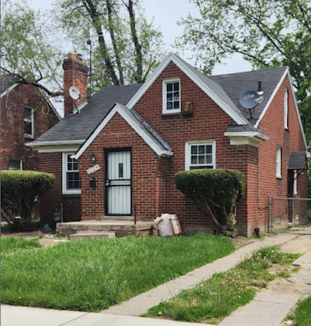 view of front of property with brick siding, a chimney, and fence