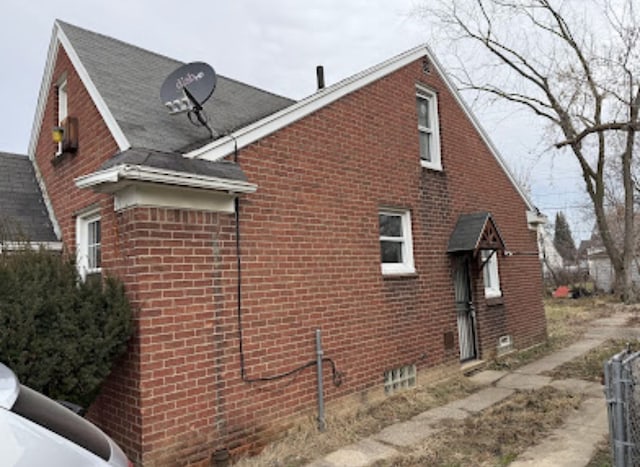 view of side of home with brick siding and fence