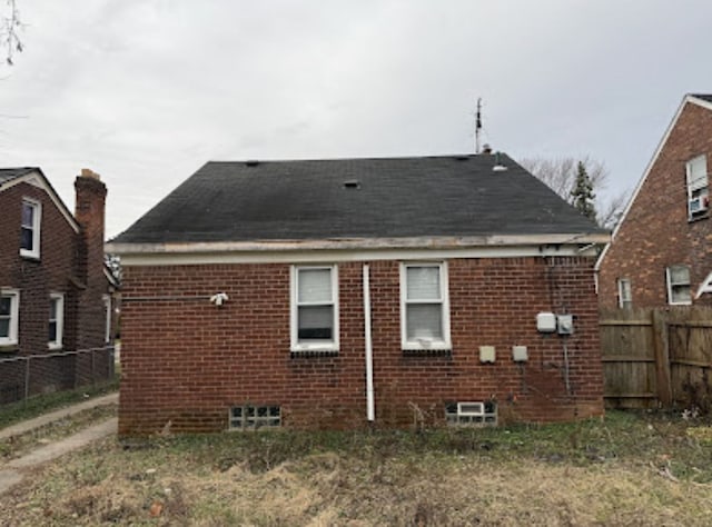 rear view of house featuring brick siding and fence