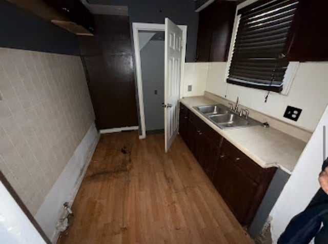 kitchen featuring light countertops, dark brown cabinets, light wood-type flooring, and a sink