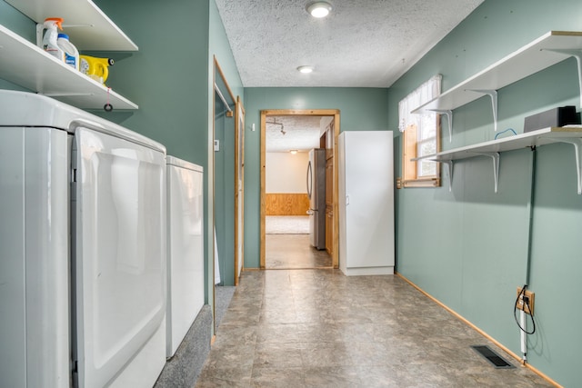 interior space featuring a wainscoted wall, visible vents, a textured ceiling, washer / dryer, and tile patterned floors