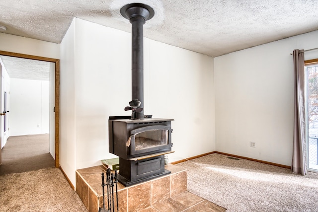 details with a textured ceiling, carpet flooring, visible vents, baseboards, and a wood stove