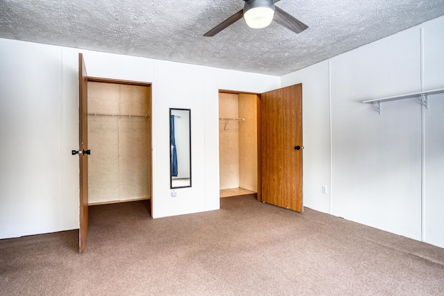 unfurnished bedroom featuring a textured ceiling, carpet flooring, a ceiling fan, a spacious closet, and a closet