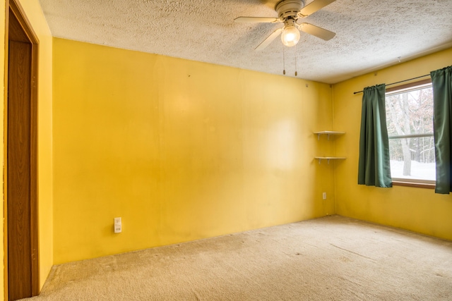 empty room with ceiling fan, carpet floors, and a textured ceiling