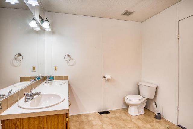 full bath with visible vents, a sink, toilet, and double vanity