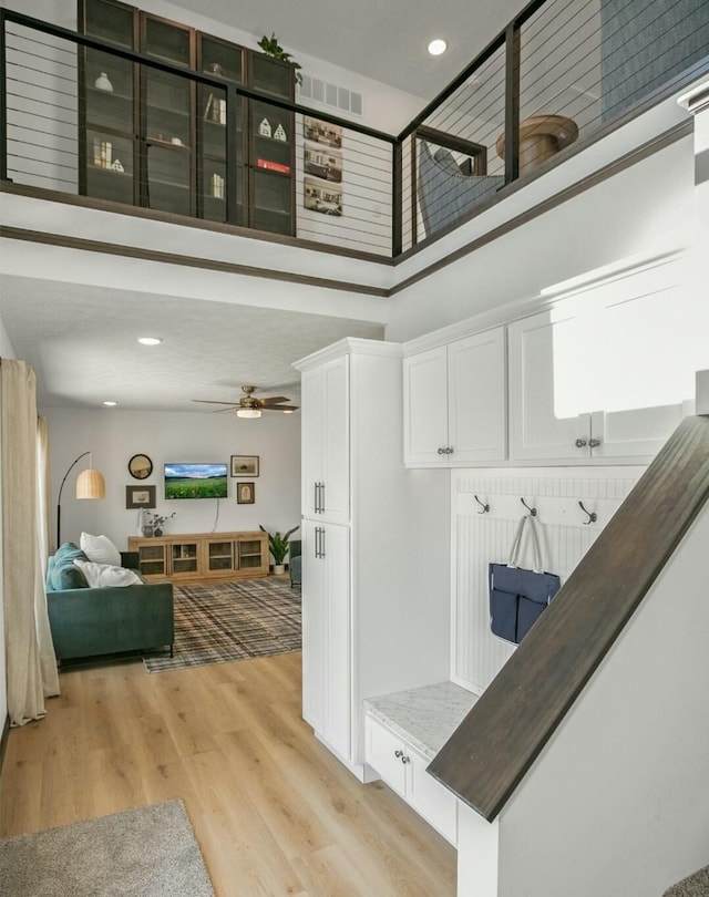 mudroom featuring ceiling fan, recessed lighting, visible vents, a towering ceiling, and light wood-style floors