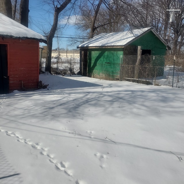 yard covered in snow featuring fence and an outdoor structure