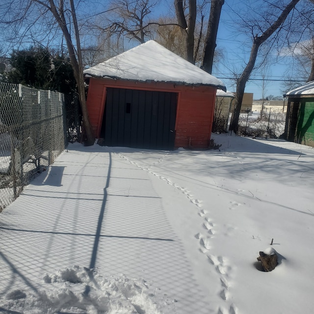 snow covered garage with fence