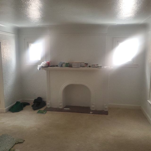 spare room with light colored carpet, baseboards, and a textured ceiling