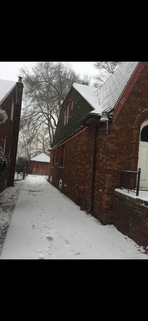 view of snowy exterior with brick siding