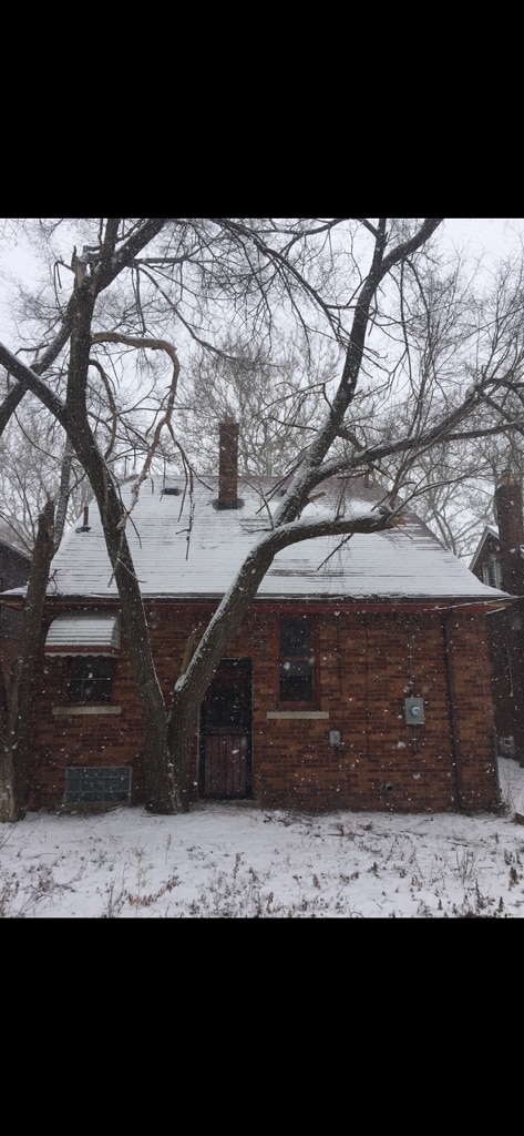 view of snow covered exterior with a chimney