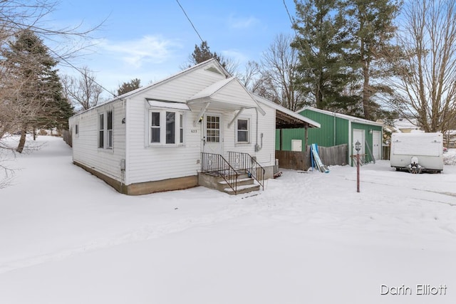 snow covered rear of property with an outbuilding