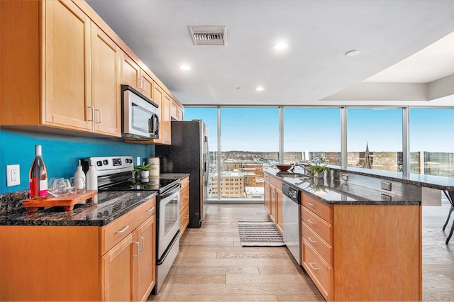 kitchen featuring a view of city, floor to ceiling windows, visible vents, appliances with stainless steel finishes, and dark stone counters