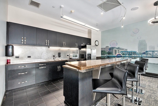 kitchen featuring a breakfast bar, a center island, visible vents, and stainless steel fridge with ice dispenser