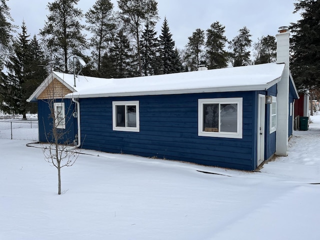 snow covered property featuring a chimney and central AC unit