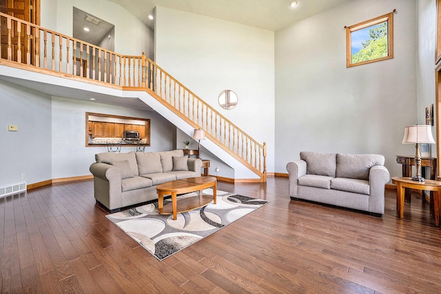living area featuring stairway, wood-type flooring, visible vents, and baseboards
