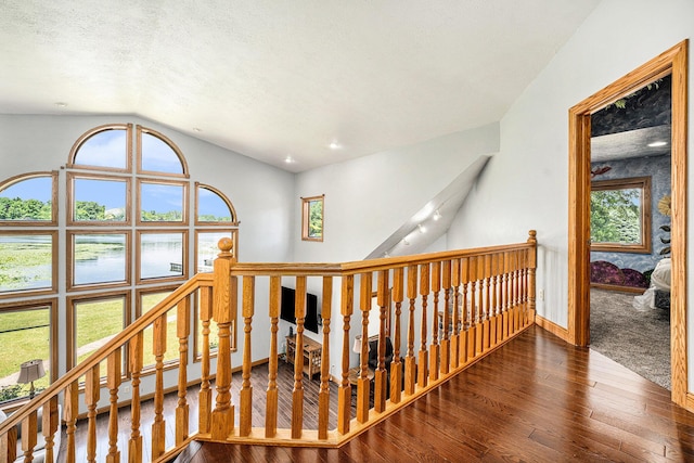 hallway featuring a wealth of natural light, lofted ceiling, an upstairs landing, and wood finished floors