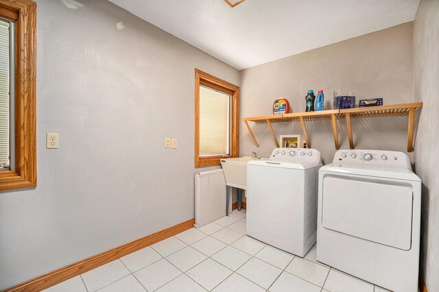 laundry room with laundry area, baseboards, separate washer and dryer, and light tile patterned flooring