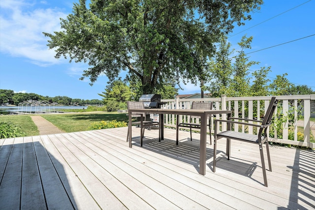 wooden deck with a water view, a grill, and a lawn