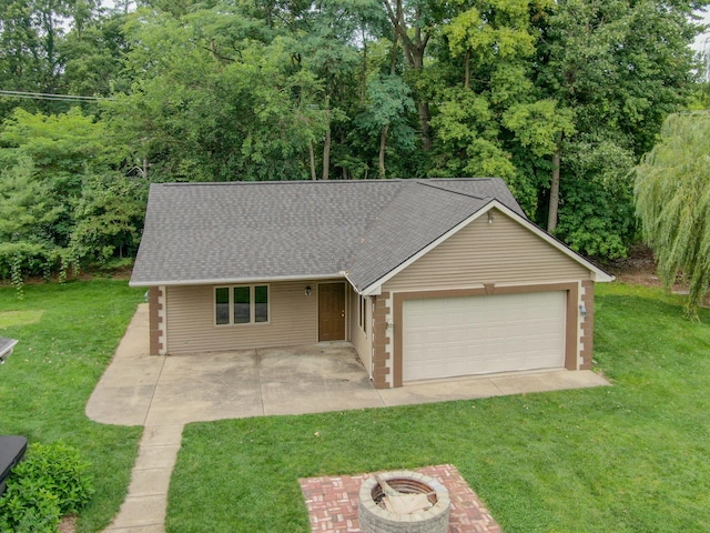 view of front of house with a shingled roof, a front yard, an outdoor fire pit, a garage, and driveway