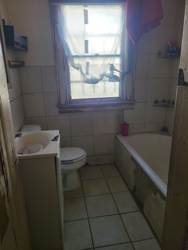 bathroom with tile patterned flooring, toilet, a bathing tub, vanity, and tile walls