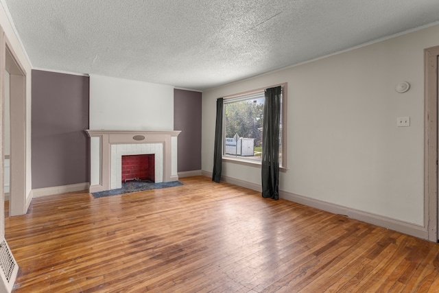 unfurnished living room featuring crown molding, light wood finished floors, a tiled fireplace, and baseboards