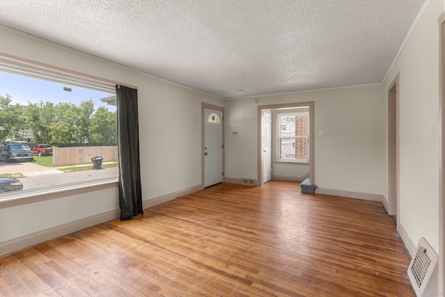 interior space with light wood-style flooring, visible vents, and crown molding