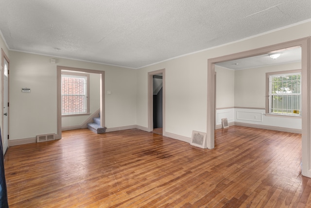 spare room featuring ornamental molding, visible vents, stairway, and wood finished floors