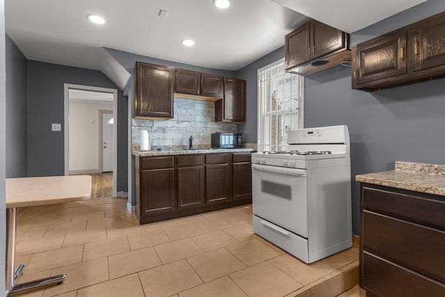 kitchen with light countertops, dark brown cabinetry, decorative backsplash, and white gas range oven