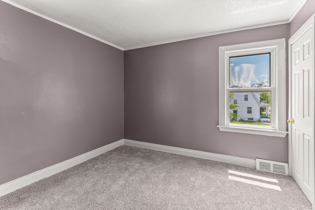 spare room featuring visible vents, baseboards, ornamental molding, carpet, and a textured ceiling